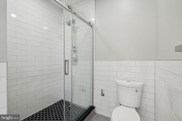 bathroom with a shower with shower door, toilet, and tile walls