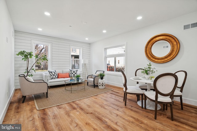 interior space with plenty of natural light, wooden walls, and light hardwood / wood-style flooring