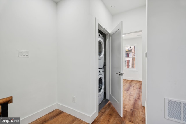 laundry area with wood-type flooring and stacked washer / drying machine