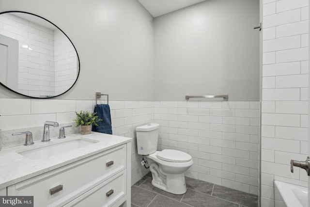 bathroom featuring toilet, vanity, tile walls, and tile patterned flooring