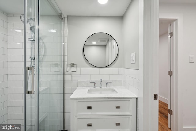 bathroom with hardwood / wood-style flooring, vanity, and an enclosed shower