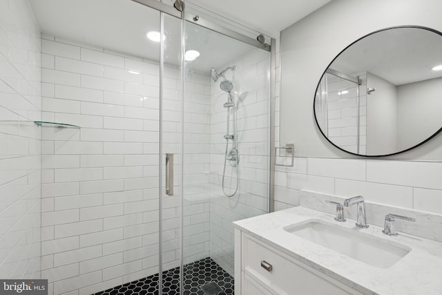 bathroom featuring vanity, an enclosed shower, and tile walls