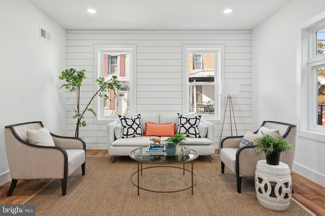 sitting room featuring plenty of natural light, wood walls, and light hardwood / wood-style flooring