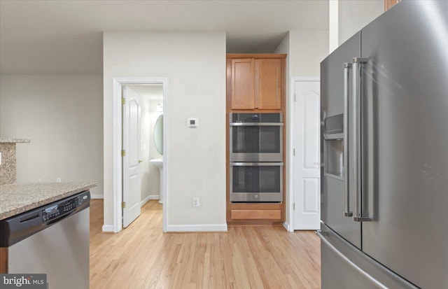 kitchen with light stone counters, stainless steel appliances, and light hardwood / wood-style floors