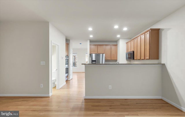 kitchen with kitchen peninsula, stainless steel fridge, and light wood-type flooring