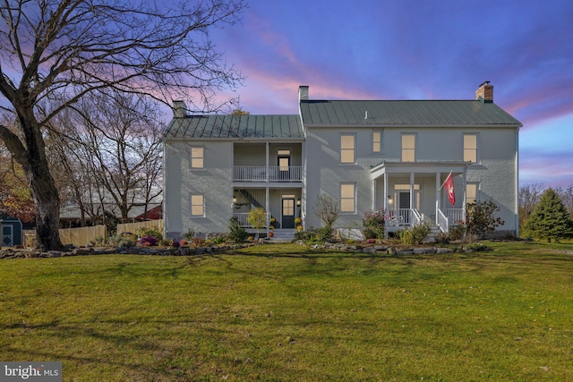 view of front of house featuring a balcony, a yard, and a porch