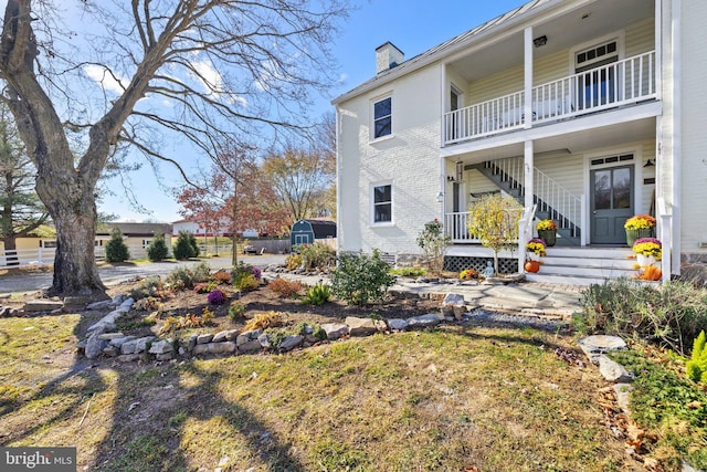 back of property with a storage unit and a balcony