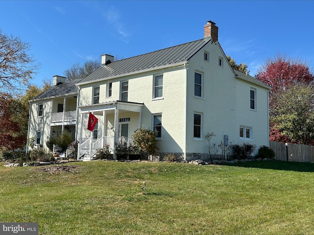 rear view of house featuring a porch and a yard