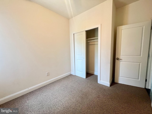 unfurnished bedroom featuring a closet and dark colored carpet