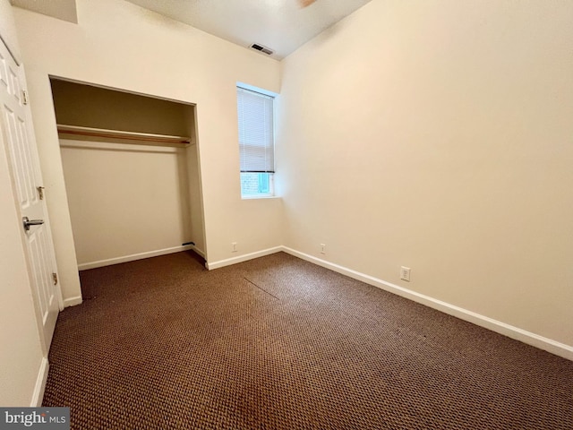 unfurnished bedroom with dark colored carpet and a closet