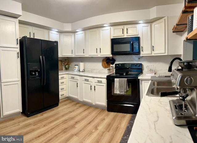 kitchen with decorative backsplash, white cabinetry, light stone countertops, black appliances, and light hardwood / wood-style floors