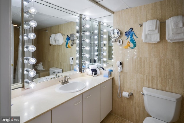 bathroom with tile walls, vanity, and toilet