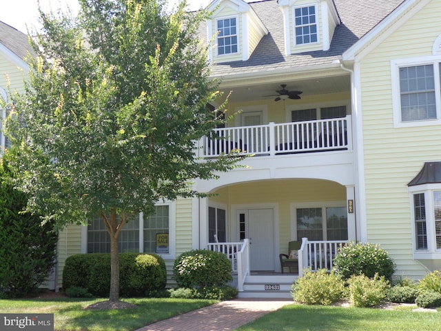 cape cod home featuring ceiling fan, covered porch, and a balcony