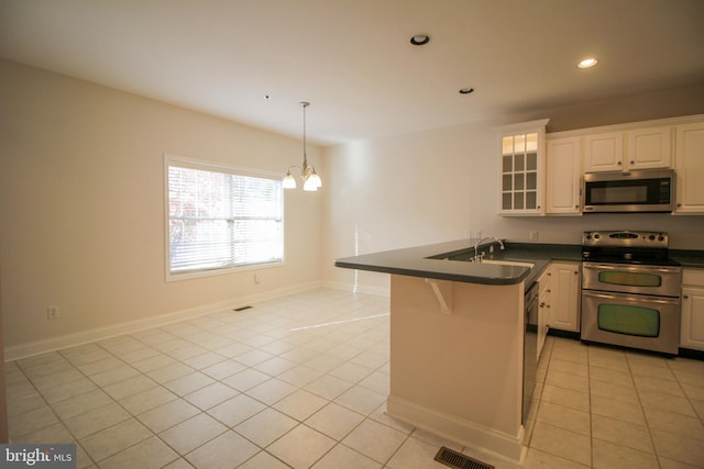 kitchen featuring stainless steel appliances, a kitchen breakfast bar, light tile patterned flooring, white cabinets, and sink