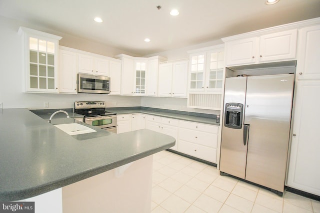 kitchen featuring kitchen peninsula, sink, light tile patterned floors, stainless steel appliances, and white cabinets