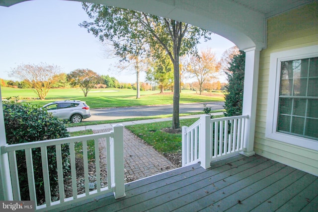 wooden deck with covered porch and a lawn