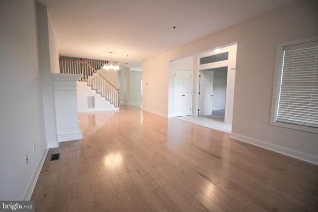 unfurnished room with an inviting chandelier and light hardwood / wood-style flooring