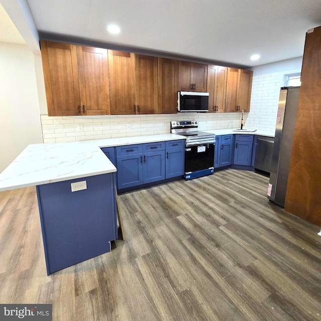 kitchen featuring stainless steel appliances, wood-type flooring, and kitchen peninsula