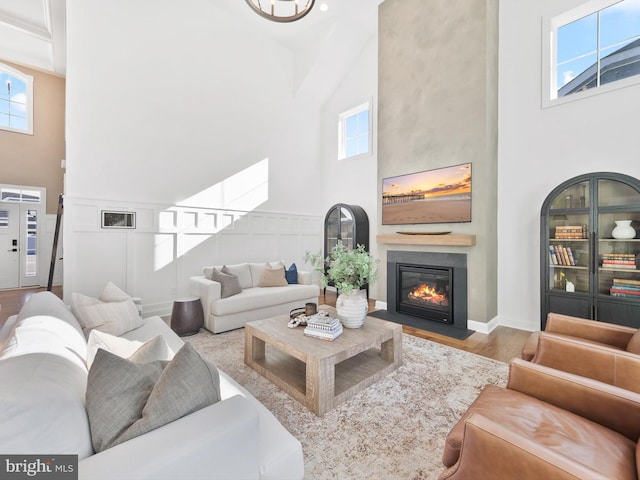 living room with light wood-type flooring and a towering ceiling