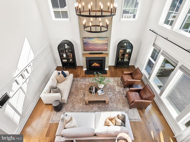 living room with a towering ceiling, hardwood / wood-style floors, and an inviting chandelier