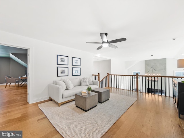 living room with ceiling fan with notable chandelier and light hardwood / wood-style floors