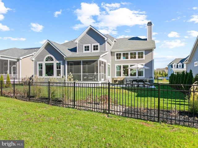 rear view of house with a lawn and a sunroom