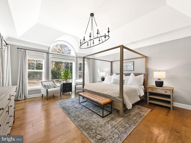 bedroom with dark hardwood / wood-style floors, a raised ceiling, and an inviting chandelier