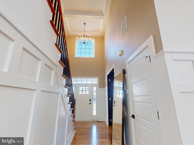 foyer entrance featuring a high ceiling, light wood-type flooring, and a chandelier