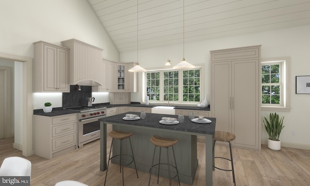 kitchen with a breakfast bar area, decorative light fixtures, light wood-type flooring, premium stove, and high vaulted ceiling