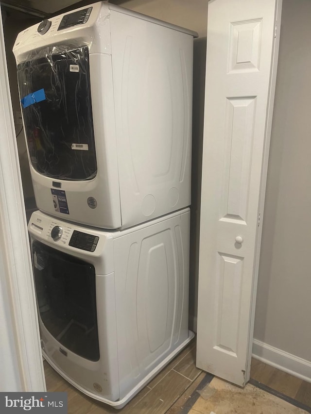 laundry room featuring stacked washer / drying machine and dark hardwood / wood-style flooring