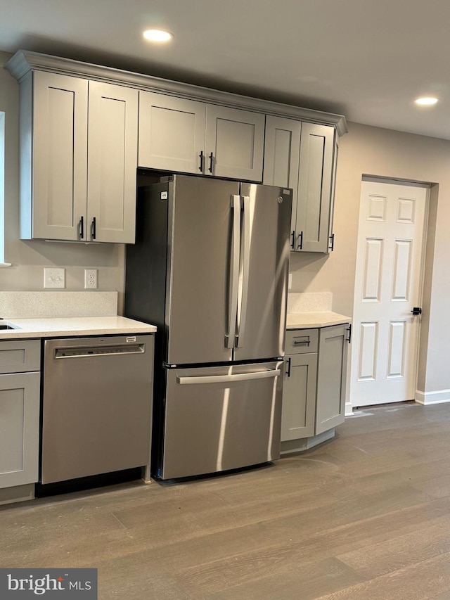 kitchen featuring stainless steel appliances, gray cabinetry, and light hardwood / wood-style flooring