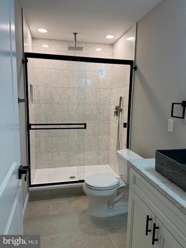 bathroom with toilet, vanity, tile patterned floors, and a shower with shower door