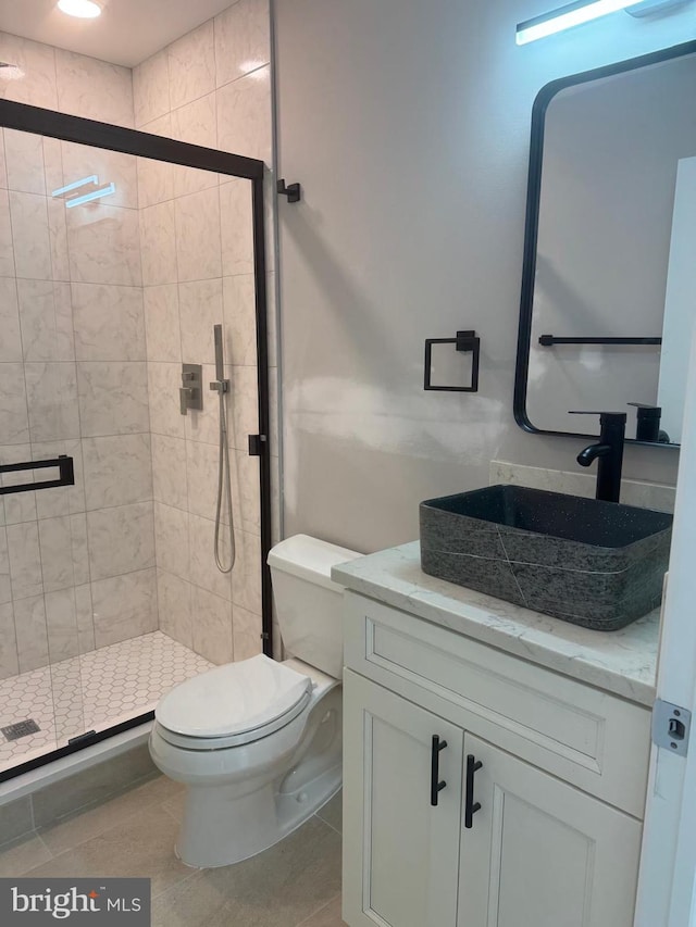 bathroom with vanity, tile patterned floors, toilet, and a shower with shower door