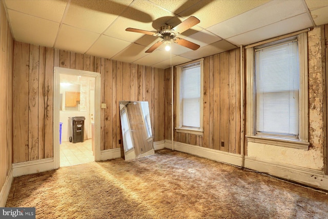 spare room featuring light carpet, wood walls, a paneled ceiling, and ceiling fan