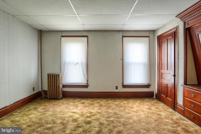 unfurnished room with radiator heating unit, light colored carpet, and a paneled ceiling