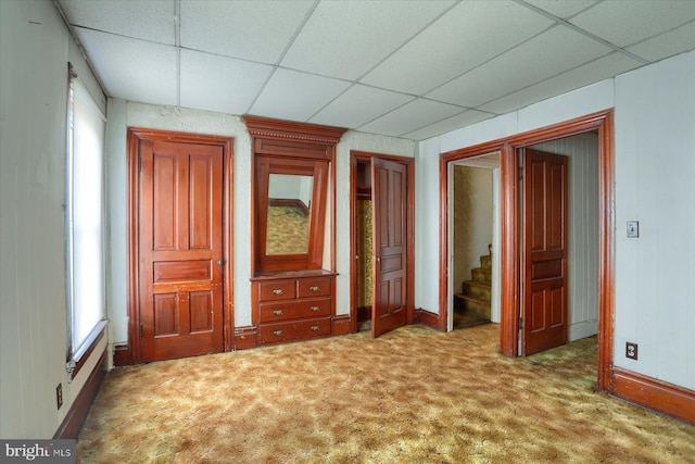 unfurnished bedroom featuring a drop ceiling and carpet flooring