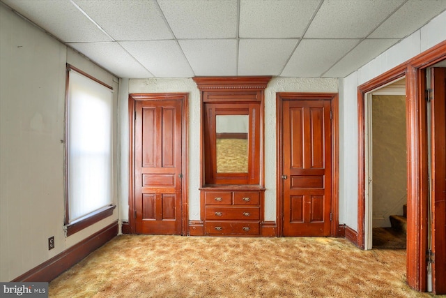 unfurnished bedroom with a paneled ceiling and light carpet