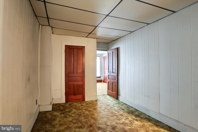 carpeted empty room featuring wooden walls