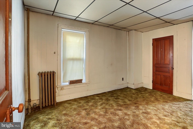 carpeted spare room with radiator and a drop ceiling