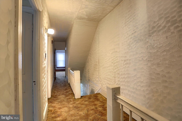 corridor with carpet floors and vaulted ceiling