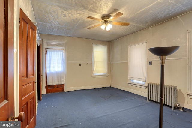 carpeted spare room featuring radiator and ceiling fan