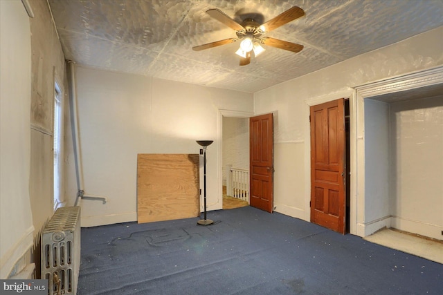 unfurnished bedroom with radiator heating unit, carpet floors, and ceiling fan