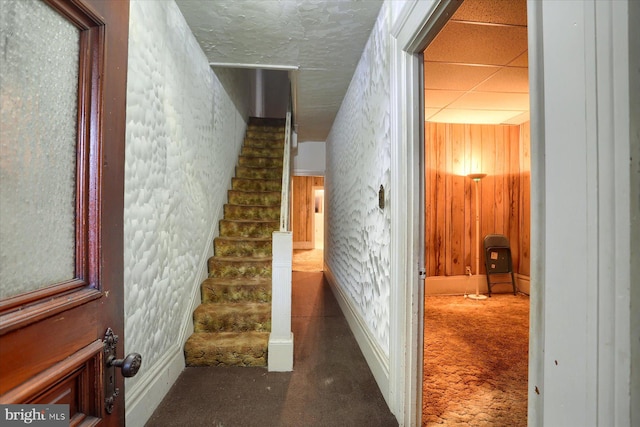 stairs with carpet floors and wood walls