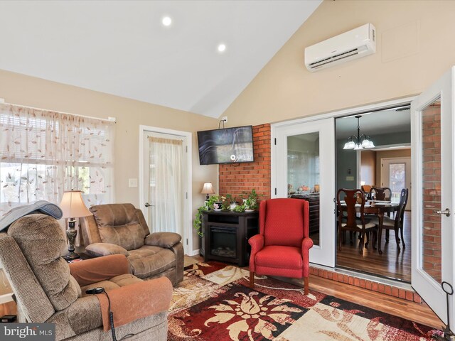 living room with an inviting chandelier, wood-type flooring, high vaulted ceiling, and a wall mounted AC