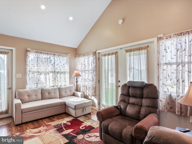 living room with plenty of natural light, light hardwood / wood-style floors, and high vaulted ceiling