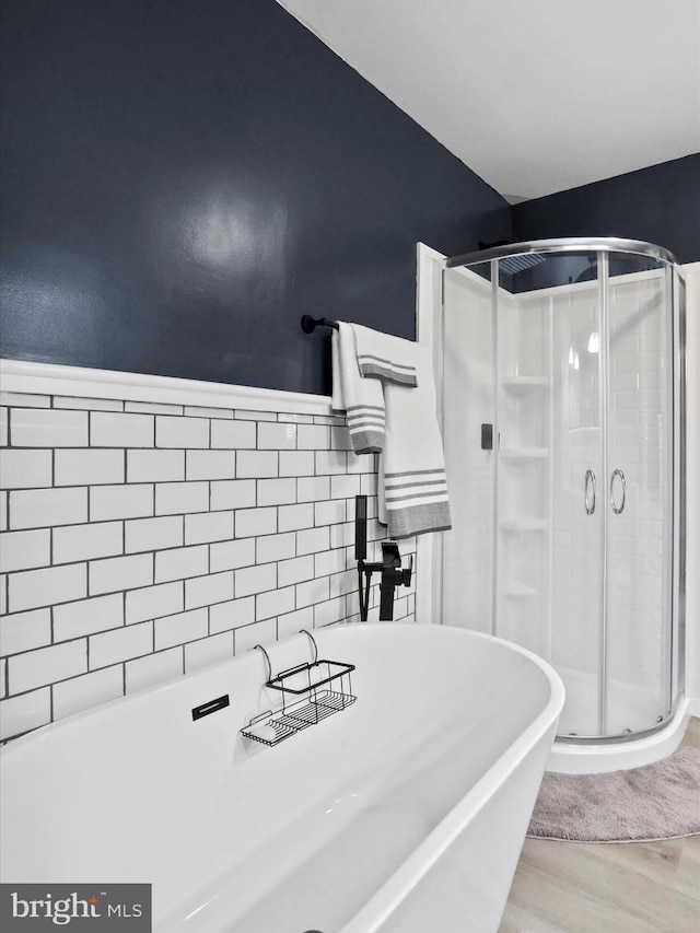 bathroom featuring wood-type flooring, tile walls, and independent shower and bath