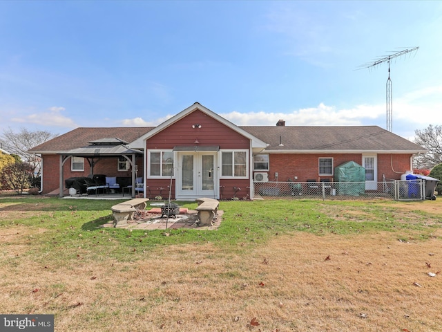 back of house with a gazebo, a fire pit, a patio, and a lawn