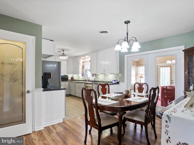 dining room featuring a chandelier, sink, and light hardwood / wood-style floors