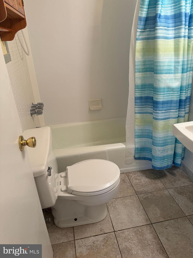 bathroom featuring tile patterned floors, toilet, and shower / bathtub combination with curtain