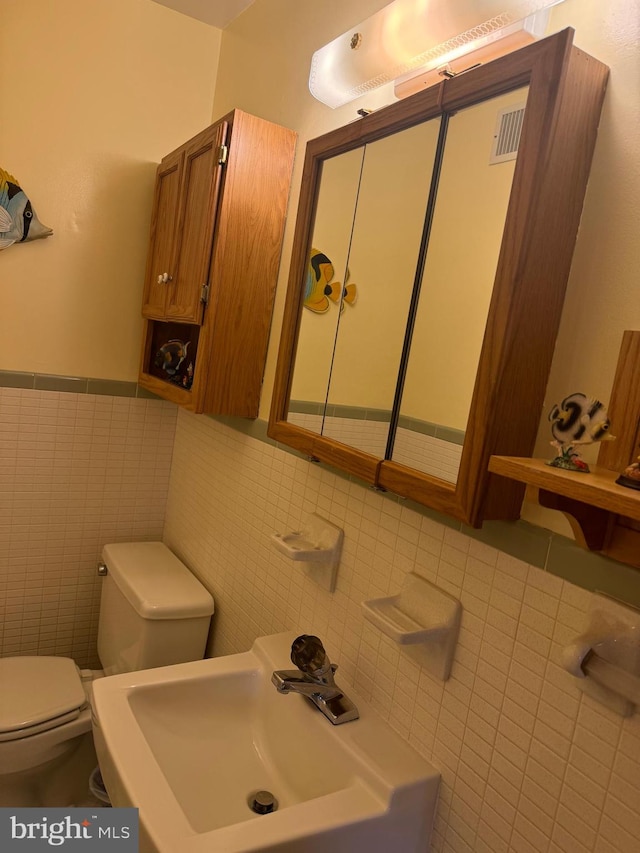 bathroom with sink, tile walls, and toilet